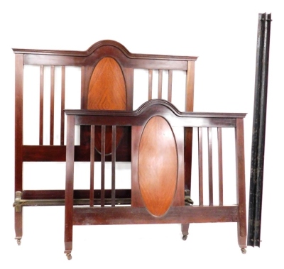 An Edwardian mahogany double bed frame, the head and foot decorated with a central oval panel of quartered mahogany, flanked by three slats, with bed base and iron side rails.