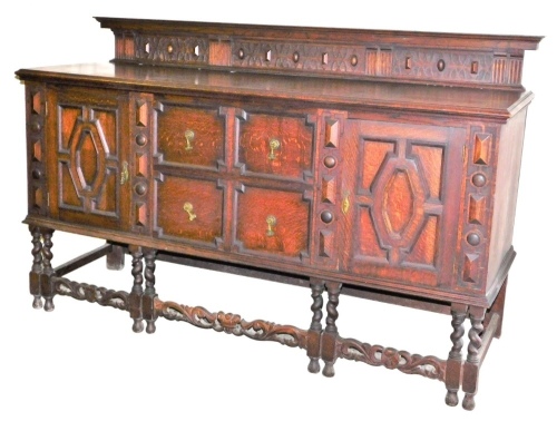 An early 20thC oak sideboard, the raised back with a moulded top and carved lattice work and geometric decoration, the base with four faux drawers flanked by two panelled cabinets, raised on six barley twist legs united by scroll carved stretchers, 116cm