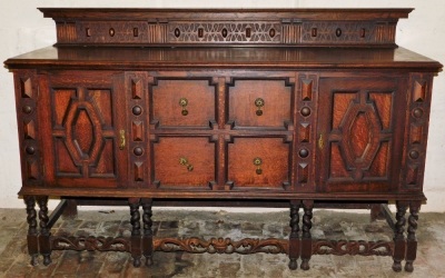 An early 20thC oak sideboard, the raised back with a moulded top and carved lattice work and geometric decoration, the base with four faux drawers flanked by two panelled cabinets, raised on six barley twist legs united by scroll carved stretchers, 116cm - 2