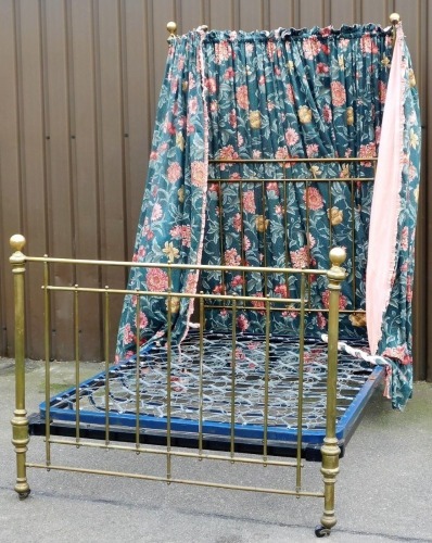 A Victorian brass framed half tester double bed, with floral fabric drapes, bed base and side bars.