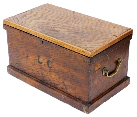 An early 20thC stained pine chest, the hinged lid enclosing a vacant interior, the front initialled L.C, with two brass handles, on a plinth base, 37cm high, 63cm wide, 37cm deep.