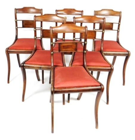 A set of eight Regency mahogany single bar back dining chairs, with brass inlay, and drop in seats, raised on sabre legs.