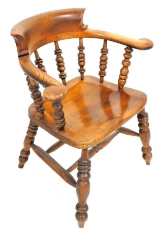 A Victorian oak and mahogany smoker's bow chair, with solid saddle seat, raised on turned legs united by a double H stretcher.