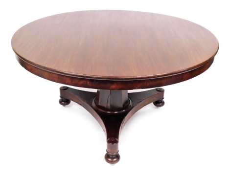 A late Regency mahogany tilt top breakfast table, the circular top raised on an out swept octagonal column over a triform base, raised on bun feet, 72cm high, 135cm diameter.