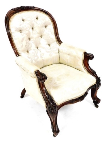 A Victorian rosewood framed spoon back armchair, upholstered in gold floral button back fabric, raised on cabriole legs, brass capped on castors, 68cm wide.