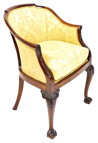 An early 20thC Georgian style mahogany tub chair, upholstered in gold floral fabric, raised on leaf carved cabriole legs, on ball and claw feet, 58cm wide.