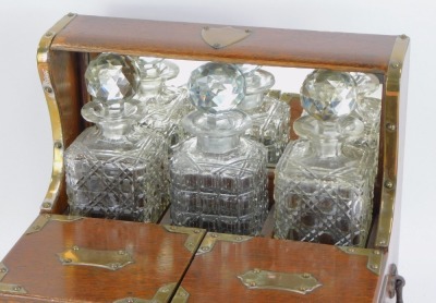 A Victorian oak Tantalus, with brass bound shield and sides, with three cut glass decanters and stoppers, and a two lidded compartment with single drawer, brass swing carry handles, 36cm high, 35cm wide, 25cm deep. - 2