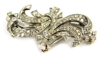 An Art Deco style diamond set clip brooch, consisting of two tied ribbon shapes, with detachable bar, with a white metal joining pin, set with one hundred and twenty round brilliant cut diamonds, ranging in size from 1.5mm to 3mm, and a group of baguette