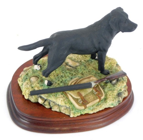 A Border Fine Arts figure of a black Labrador, near hunting bag and rifle, stamped BFA Scotland, dated 1988, 13cm high, 20cm wide. (AF)