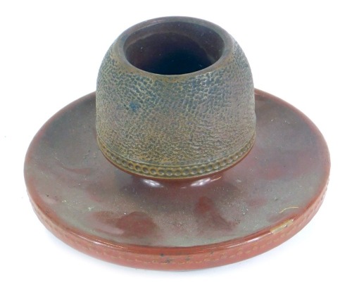 A late 19thC pottery match strike, the shaped top with centre for matches, on a circular foot, 13cm diameter.