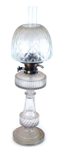 An early 20thC cut glass oil lamp, with an oval reservoir on a shaped and twist stem, on circular foot with diamond pressed shade and chimney, 59cm high. (AF)