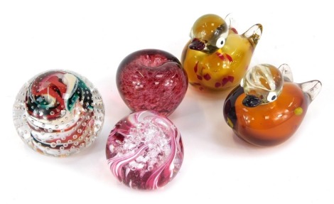 A collection of art glass, comprising two moulded glass ducks, 10cm high, a glass apple paperweight, 8cm high, an Ingrid Pears Hot Glass Studio of Newark swirl and bubble paperweight, 8cm high, and a Langham pink bubble glass paperweight, 8cm high. (5)