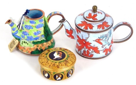 Two Trade It Aid painted enamel teapots, comprising number 686, and H159, 6cm high, one lacking lid, and a Buckingham Palace enamel pill box, 5.5cm wide. (3)