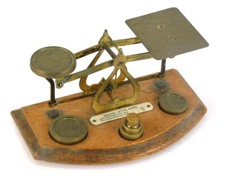 A set of 19thC brass letter scales, with weights, on an oak base, 10cm high, 20cm wide, 11cm deep.