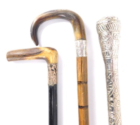 Three walking sticks, comprising two horn and white metal collared walking sticks, and an Eastern inspired plated foliate engraved walking stick, the longest 93cm long. (3)