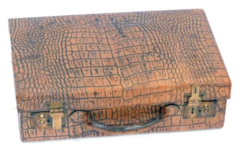 An early 20thC faux crocodile skin tan leather suitcase, 14cm high, 40cm wide, 25cm deep.