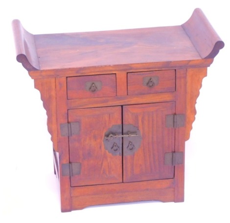 A Chinese mahogany table top cabinet, with an altar top above an arrangement of two drawers over two cupboards, 45cm high, 50cm wide, 26cm deep.