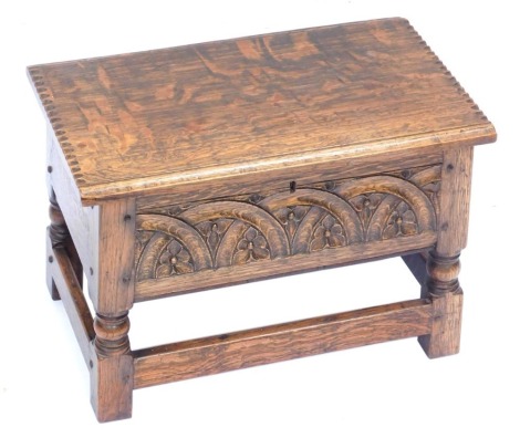 An early 20thC oak sewing box, with a carved fret and arch front, raised on turned and square legs united by a box stretcher, 32cm high, 48cm wide, 29cm deep.