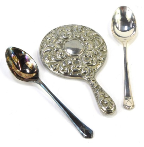 Three items of silver, comprising two silver Fiddle pattern and golf design teaspoons, and a silver handled miniature hand held dressing table mirror, 10cm high, 3.47oz gross. (3)