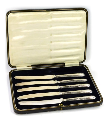 A cased set of five white metal handled butter knives, with stainless steel blades, in fitted case.