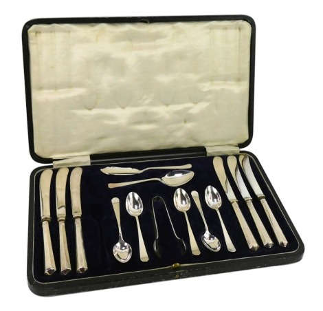 A George V silver presentation dessert case, in the Art Deco style, comprising six silver handled cake knives, a set of five silver teaspoons, a pair of silver sugar tongs and a cake slice, Sheffield 1928, in fitted case, 2.0oz. (one piece missing)