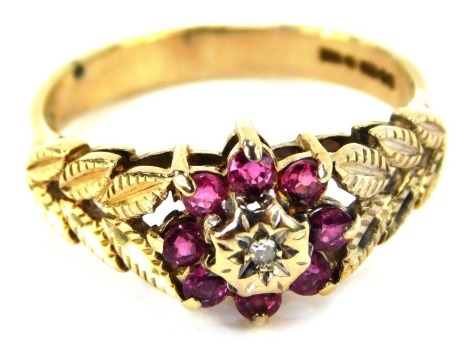 A 9ct gold floral cluster dress ring, the central emblem set with garnets, with leaf moulded shoulders and a cz set centre, ring size N½, 2.8g all in.