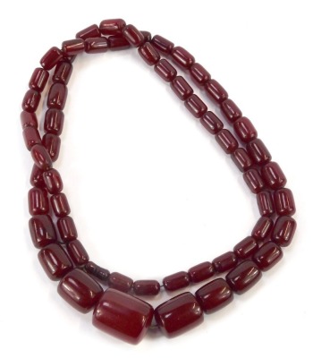 A cherry amber beaded necklace, with oblong faceted graduated beads, the largest 2.5cm wide, the smallest 1cm wide, on a knotted string strand, 88.3g all in.