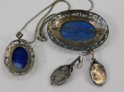 A lapis lazuli jewellery suite, comprising large oval brooch, with pierced border, white metal stamped 925, 8cm x 6cm, a similar design pendant, 6.5cm high, on modern chain, 40cm long, and a pair of matched drop earrings, white metal unmarked 5cm high, 89 - 2