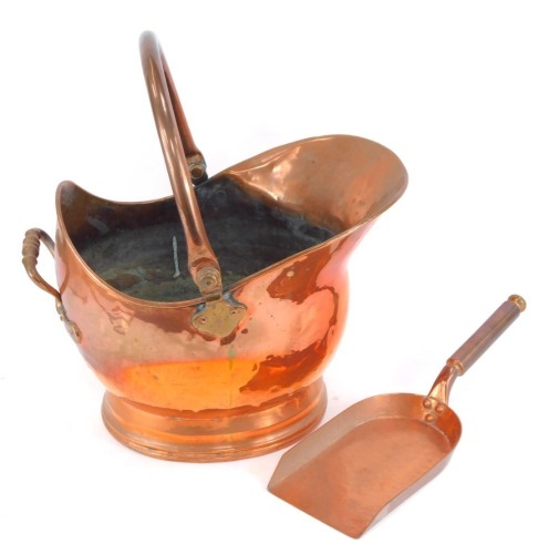 A Victorian copper helmet shaped coal scuttle, with a copper shovel.