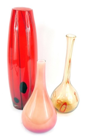 A group of art glass, comprising a large red and black striped vase, 53cm high, with artificial flowers, a pink two tone squat vase, 34cm high, and an orange and red circle blown glass vase, 40cm high. (3)