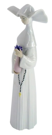 A Lladro porcelain figure of a Nun carrying vase of flowers, 26cm high.