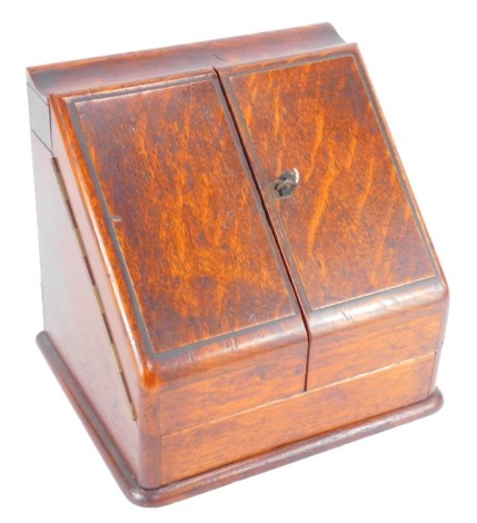 A Victorian oak stationary box, with two doors opening to reveal a fitted interior with waterfall stationery rack, pen tray and inkwell, above a single drawer, 36cm high, 30cm wide, 23cm deep.