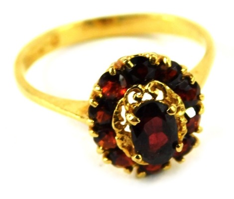 An oval garnet set ring, in a yellow metal basket setting, stamped 750, size L, 2.9g.