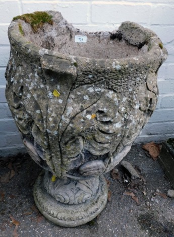 A reconstituted stone garden urn, of circular form decorated with scrolling leaves, on a stepped and circular foot, 70cm high. (AF)