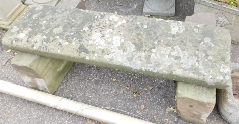 A stone garden bench, formed as heavy plinth on two supports, 40cm high, 114cm wide.