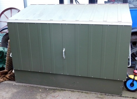 A metal log store, in a green and light green finish, with a lift hinged lid, 137cm high, 184cm wide, 89cm deep, and rubber ground mats.