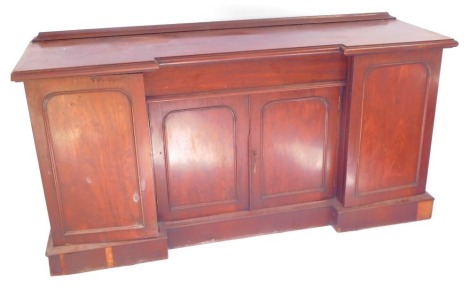 A Victorian mahogany breakfront sideboard, a central cushion drawer over a pair of panelled doors, flanked by further doors enclosing a wine cooler and shelves, raised on a plinth base, 92cm high, 184cm wide, 58.5cm deep.