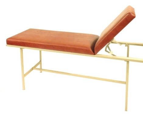 A 20thC metal framed medical examination couch, upholstered in red leatherette, with an adjustable head rest, 73cm high, 183cm wide, 60cm deep.