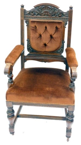 A Victorian oak open armchair, with shell and foliate carved crest rail, button back and seat upholstered in brown draylon, raised on cup and cover supports united by an H framed stretcher, 60cm wide.