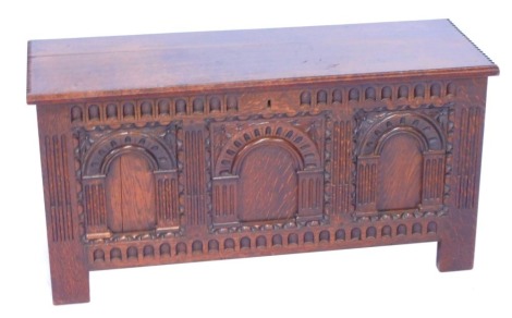 A 17thC style oak blanket box, the hinged lid opening to reveal a vacant interior, the triple panel front carved with arched recesses and flowers, raised on stiles, 53cm high, 106cm wide, 39cm deep.