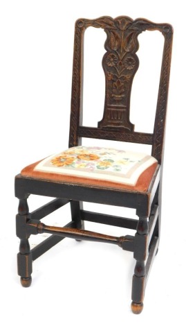 A Victorian carved oak dining chair, the crest and splat decorated with a vase of flowers and leaves, with drop in seats, raised on turned legs, united by stretchers.