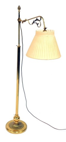 A late Victorian brass gasolier standard lamp, converted to electricity, the branch with foliate scrolling, terminating in a pleated shade, raised on a fluted column and semi fluted circular base, 143cm high.