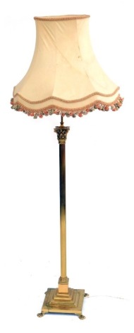 A brass Corinthian column standard lamp, raised on a stepped square base on lion's paw feet, with a cream coloured shade, 178cm high.