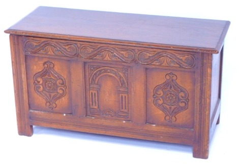 A 17thC style oak blanket chest, the hinged lid opening to reveal a vacant interior, above a foliate carved frieze and three panels carved with a central arch flanked by floral motifs, raised on stiles, 51cm high, 91cm wide, 40cm deep.