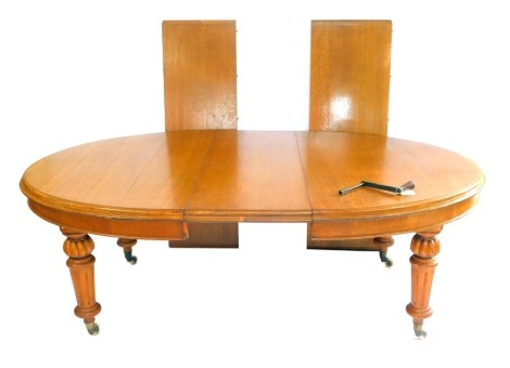 A Victorian light oak wind out dining table, with three additional leaves, raised on fluted and turned legs, brass capped on castors, 73cm high, 156cm wide, 287cm extended, 129cm deep.