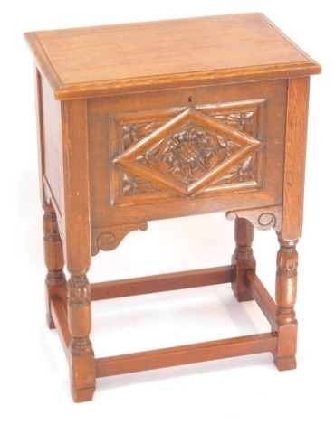 An early 20thC oak sewing box, the hinged lid opening to reveal a fitted tray and silk lined interior, rose carved panel front, raised on turned legs, united by a box stretcher, 64cm high, 47cm wide, 31.5cm deep.