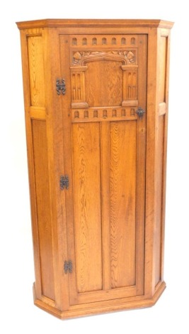 An early 20thC oak hall robe, with a carved panelled door, opening to reveal hanging hooks and a glove box, raised on a plinth base, 168cm high, 88cm wide, 40cm deep.