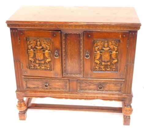 An oak sideboard, with two panelled doors carved with armorials, over a pair of frieze drawers, raised on acorn turned supports united by stretchers, 84cm high, 90cm wide, 42cm deep.