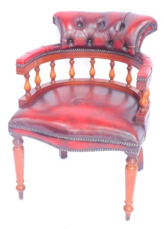 A reproduction mahogany and red leather smokers bow chair, with a serpentine seat, raised on turned legs, 60cm wide.