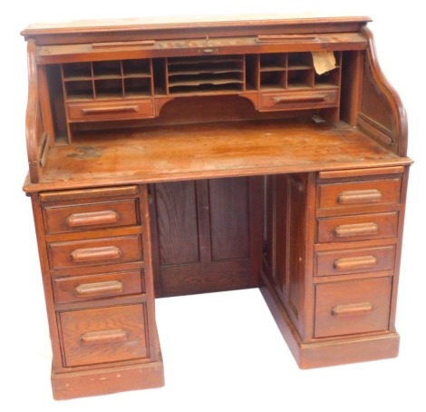 A Victorian oak tambour fronted office desk, the tambour front opening to reveal two drawers and recesses, over twin pedestals of four drawers, raised on plinth bases, brass lock plate stamped HLL Entirely English Make, 122cm high, 126cm wide, 77.5cm deep